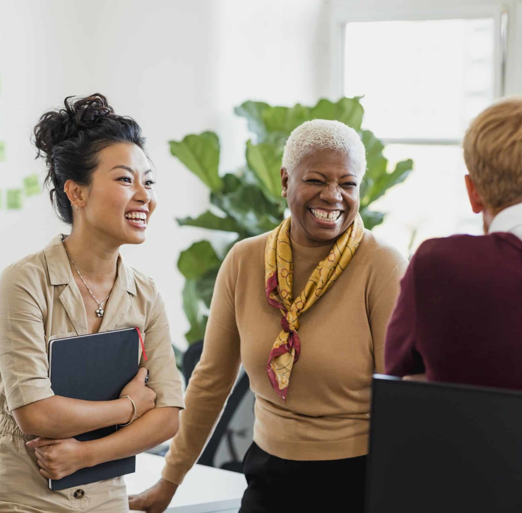 3 women talking and smiling in a professional setting