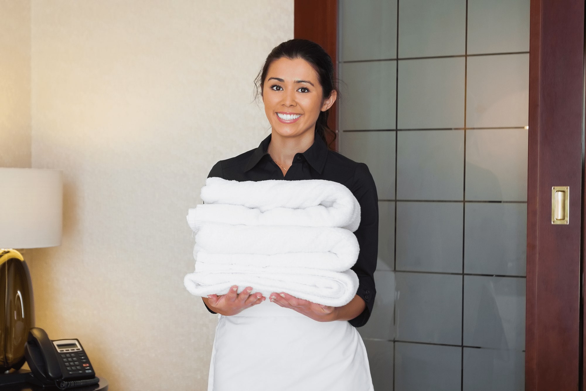 A woman holding towels while working in a hotel.