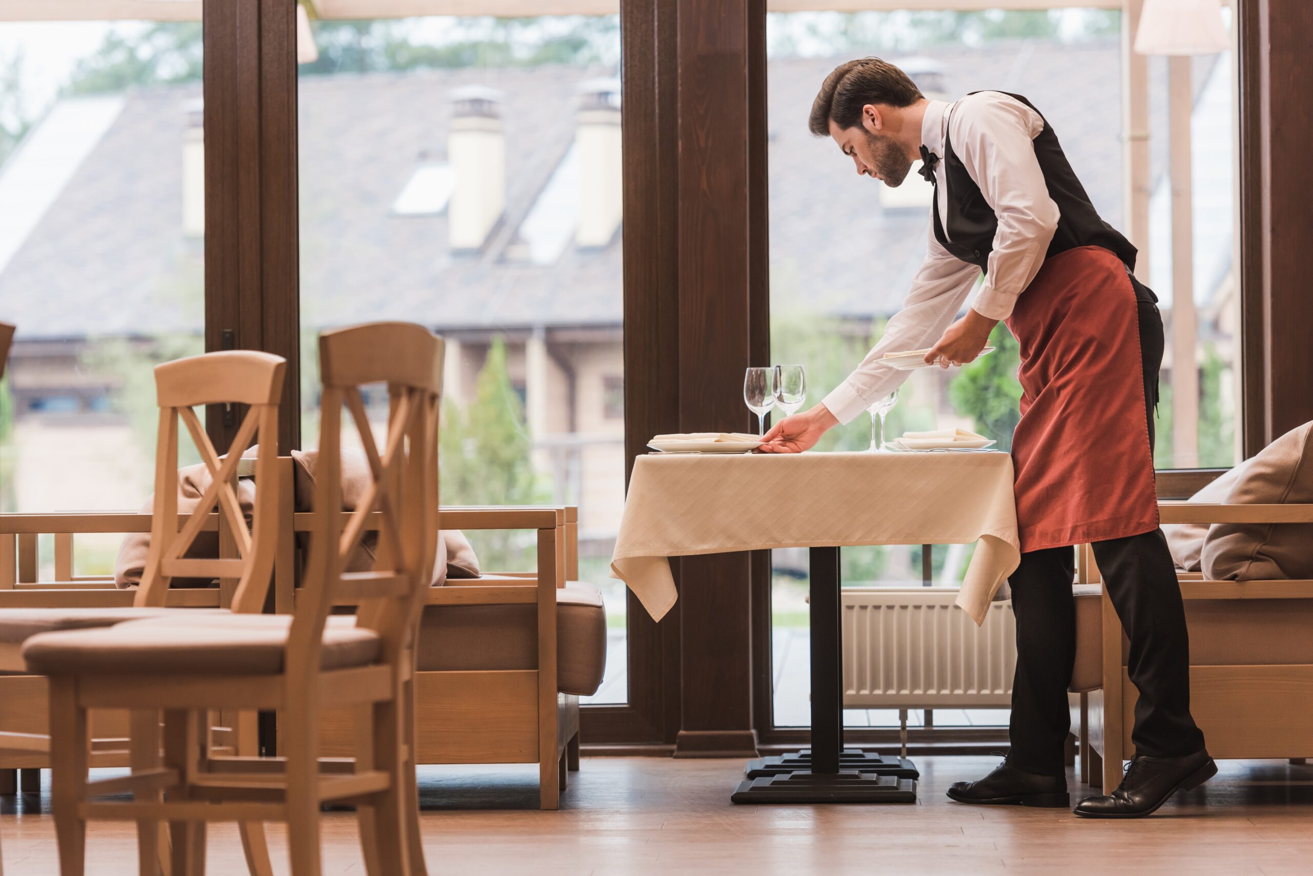 Side view of Waiter serving plates on a table at the restaurant