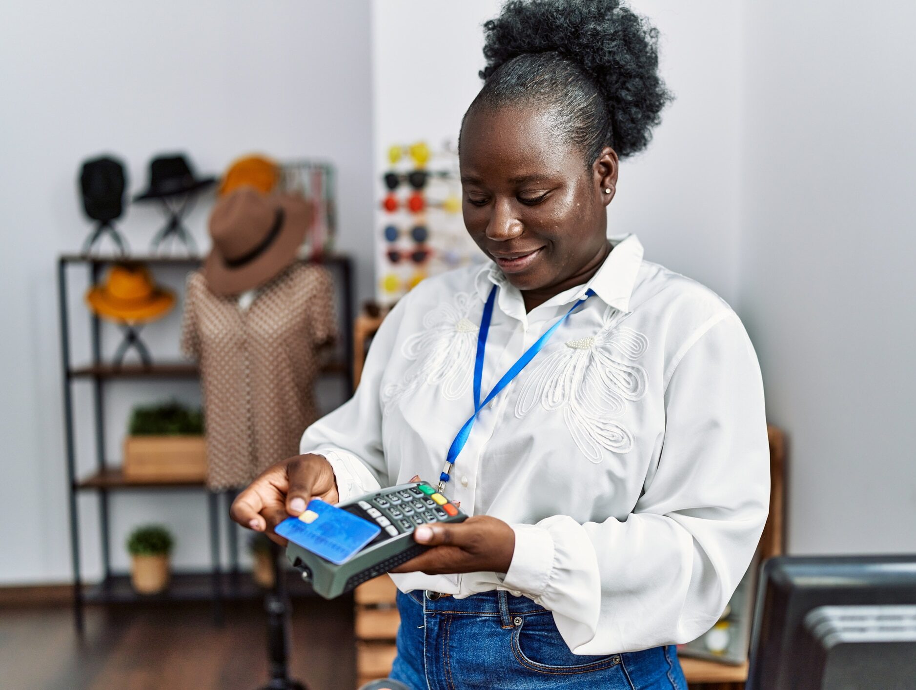 Young african american woman shopkeeper smiling confident using credit card and data phone at clothing store