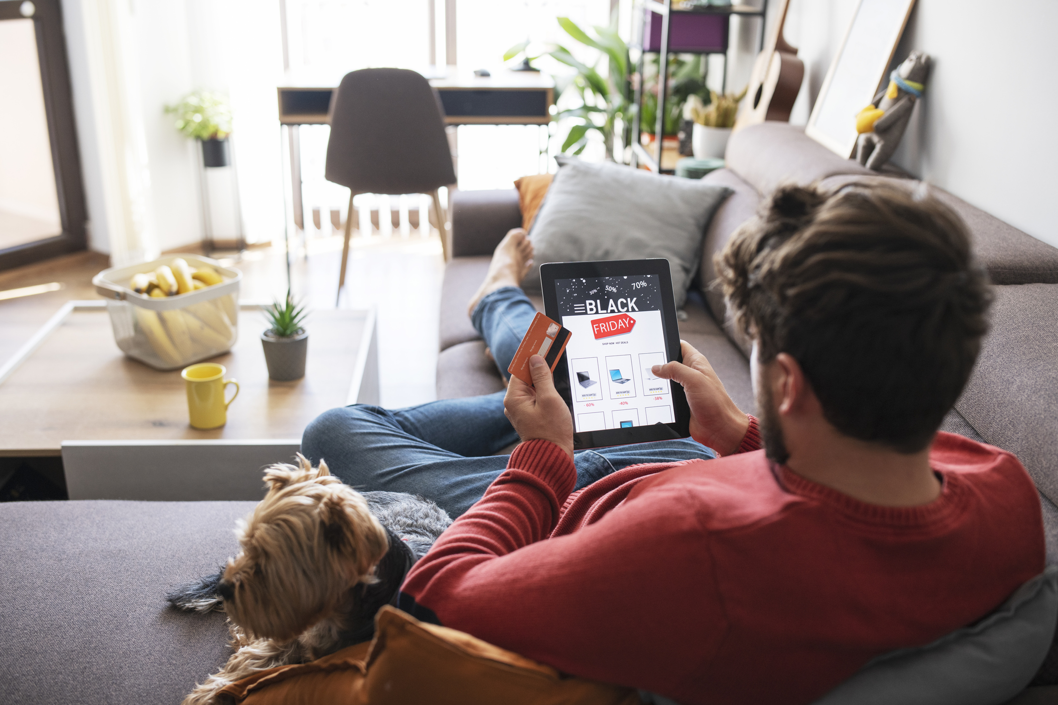 Man and his dog relaxing at home and shopping electronics online during Black Friday sale.